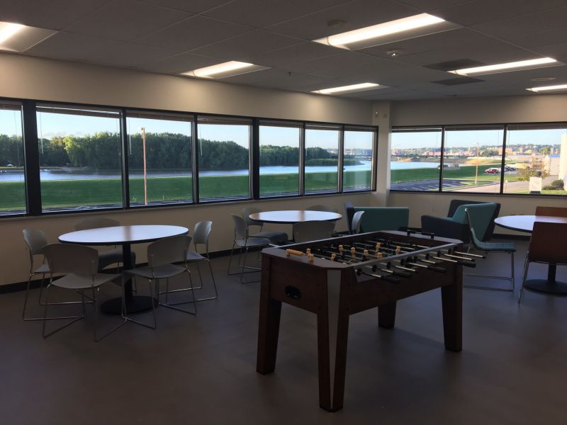 lunch room at American Customer Ccare with lunch tables and chairs and a Foosball table